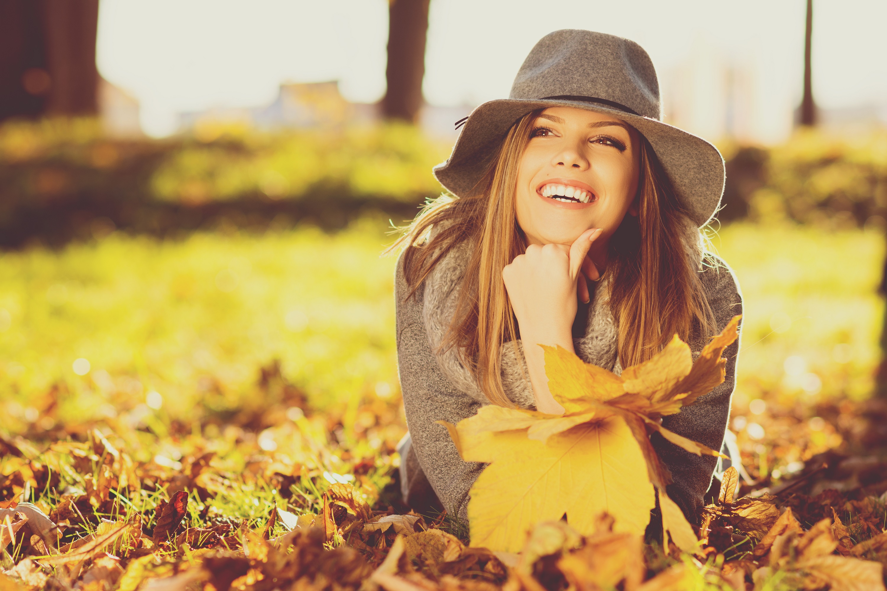 Young woman with perfect smile relaxing in the fall park.