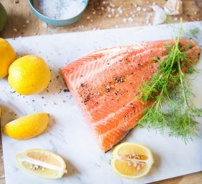 Fresh salmon with spices , dill and lemons on the chopping board.