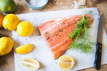 Fresh salmon with spices , dill and lemons on the chopping board.