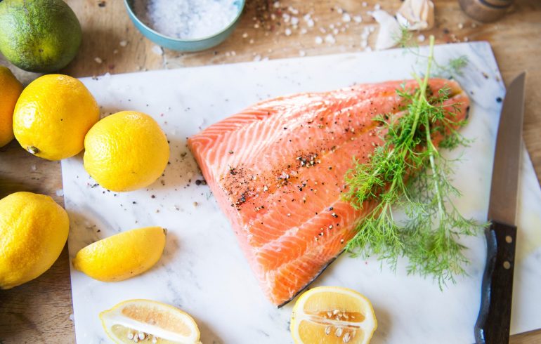 Fresh salmon with spices , dill and lemons on the chopping board.