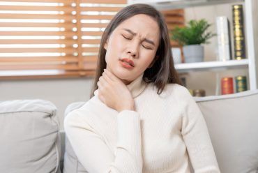 A woman massaging her neck due to pain caused by teeth grinding.