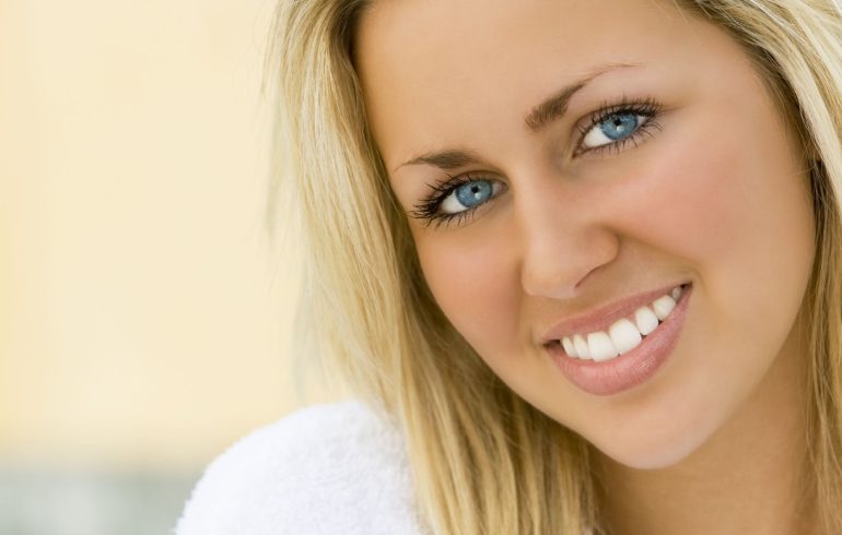 A blonde-haired gorgeous woman with a perfect smile after professional teeth whitening.