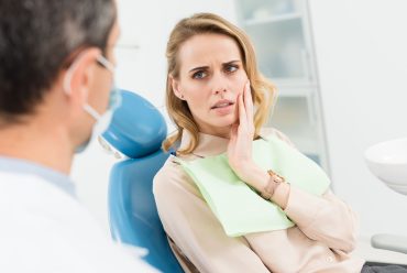 concerned stressed woman in a dental chair talking to a dentist