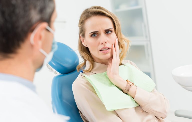 concerned stressed woman in a dental chair talking to a dentist