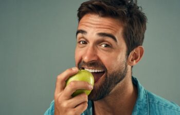Studio portrait of a handsome young man about to bite into an apple.