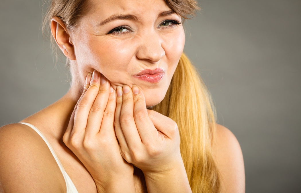 Dental care and toothache. Young woman achy girl suffering from terrible tooth pain touching pressing her cheek by hand palm.