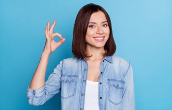 a young woman with perfect smile showing ok sign with her fingers