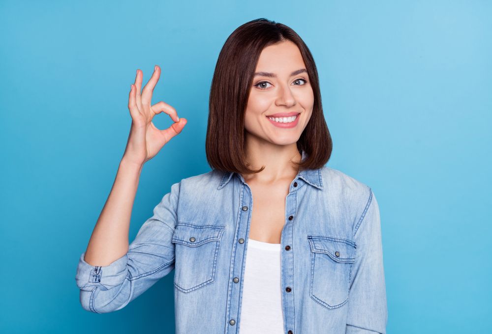 a young woman with perfect smile showing ok sign with her fingers