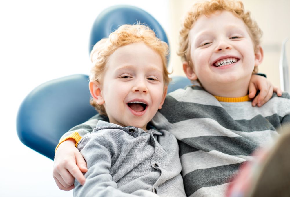 Portrait of a happy young brothers sitting on the dental chair at the dental office