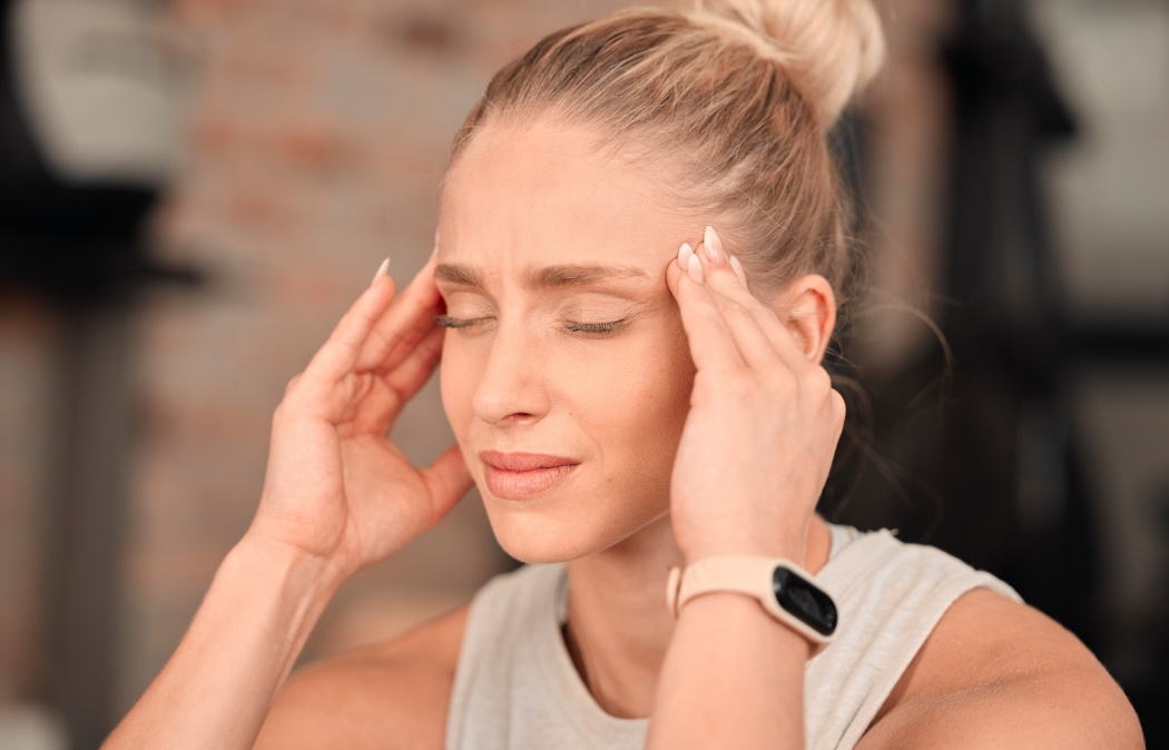 Woman, headache and pain at gym for fitness, exercise anxiety and workout challenge. Face of female athlete with migraine, sports injury and frustrated in struggle of training problem, sick and tired