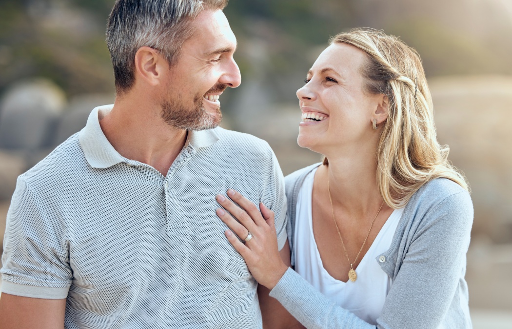 Laughing, happy man and woman at beach for love, trust and care or support for relationship. Together, couple and smile in nature for date or travel, marriage and joke or humour for outdoor adventure